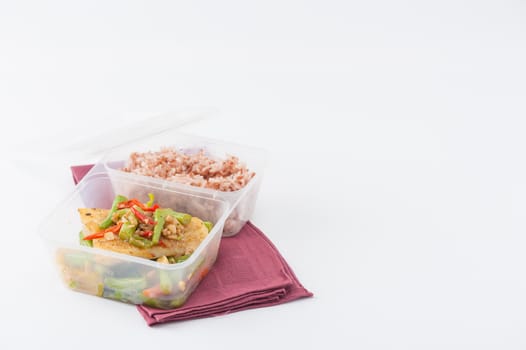 Pangasius fish fried with chili and vegetables cooked by clean food concept with brown rice in lunch box on white table