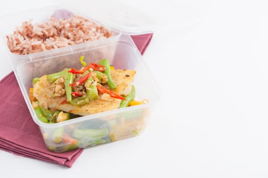 Pangasius fish fried with chili and vegetables cooked by clean food concept with brown rice in lunch box on white table