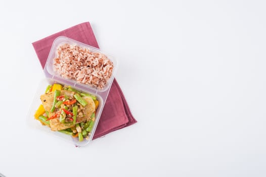 Pangasius fish fried with chili and vegetables cooked by clean food concept with brown rice in lunch box on white table