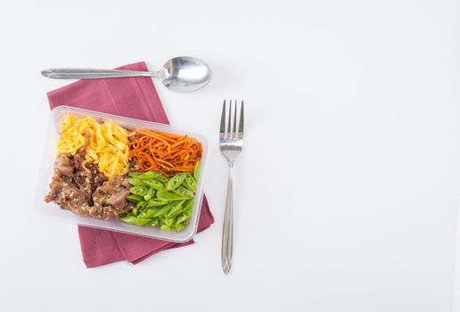 Bibimbub in clean food style. Brown rice with roasted pork, egg, and vegetables on white table