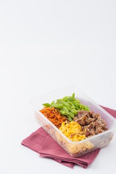 Bibimbub in clean food style. Brown rice with roasted pork, egg, and vegetables on white table