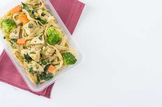 Fettuccine pesto sauce with spinach, grilled fish and vegetables cooked by clean food concept in lunch box on white table