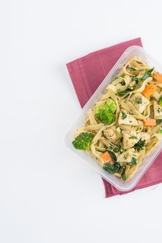 Fettuccine pesto sauce with spinach, grilled fish and vegetables cooked by clean food concept in lunch box on white table