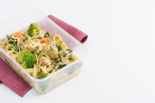Fettuccine pesto sauce with spinach, grilled fish and vegetables cooked by clean food concept in lunch box on white table