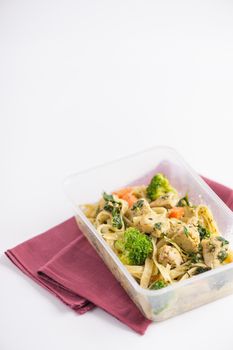 Fettuccine pesto sauce with spinach, grilled fish and vegetables cooked by clean food concept in lunch box on white table