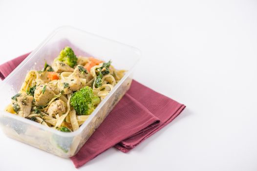 Fettuccine pesto sauce with spinach, grilled fish and vegetables cooked by clean food concept in lunch box on white table