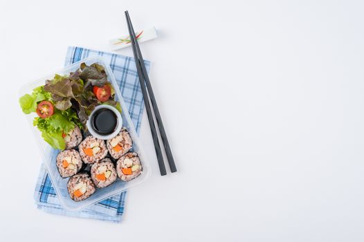 Japanese style brown rice maki with grilled chicken, grilled pork, and grilled tofu cooked by clean food concept in lunch box on white table