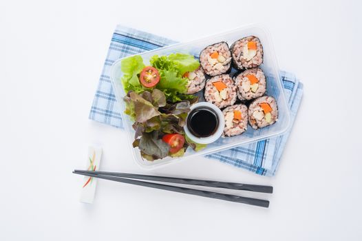 Japanese style brown rice maki with grilled chicken, grilled pork, and grilled tofu cooked by clean food concept in lunch box on white table