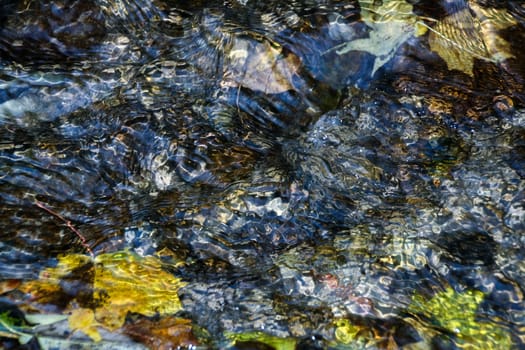 background of pebbles seen through rippling water in the sun