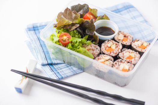 Japanese style brown rice maki with grilled chicken, grilled pork, and grilled tofu cooked by clean food concept in lunch box on white table