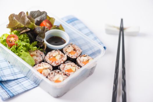 Japanese style brown rice maki with grilled chicken, grilled pork, and grilled tofu cooked by clean food concept in lunch box on white table