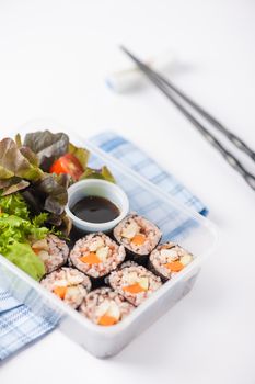 Japanese style brown rice maki with grilled chicken, grilled pork, and grilled tofu cooked by clean food concept in lunch box on white table