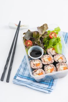 Japanese style brown rice maki with grilled chicken, grilled pork, and grilled tofu cooked by clean food concept in lunch box on white table