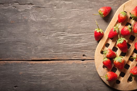 Strawberries on wood background in vintage style with low key scene.
