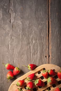 Strawberries on wood background in vintage style with low key scene.