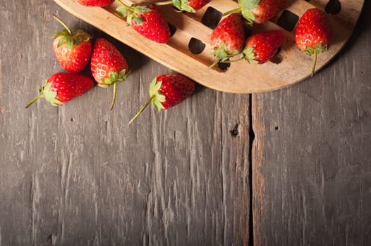 Strawberries on wood background in vintage style with low key scene.