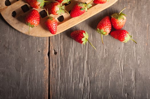 Strawberries on wood background in vintage style with low key scene.