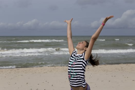 Girl with hands held high on the beach.