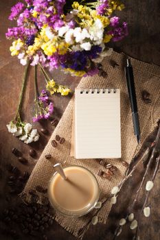 Notepad with pen, a glass of Thai tea and bits of red velvet cake on rustic wood background with low key scene