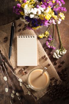 Notepad with pen, a glass of Thai tea and bits of red velvet cake on rustic wood background with low key scene