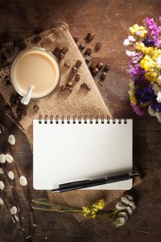 Notepad with pen, a glass of Thai tea and bits of red velvet cake on rustic wood background with low key scene