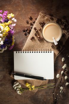 Notepad with pen, a glass of Thai tea and bits of red velvet cake on rustic wood background with low key scene
