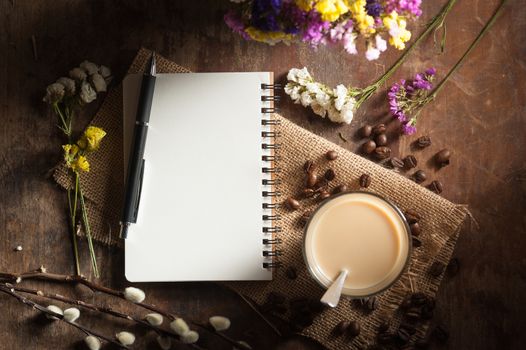 Notepad with pen, a glass of Thai tea and bits of red velvet cake on rustic wood background with low key scene