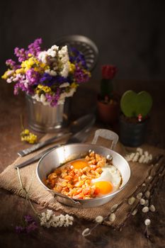 Vietnamese style fried egg in metal pan with white pork and onion on wood table in vintage style with low key scene