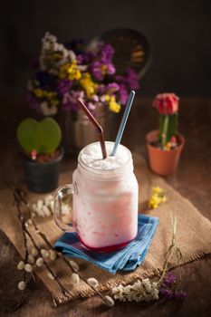 Fresh milk with red syrup on wood table in cafe with low key scene