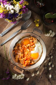 Vietnamese style fried egg in metal pan with white pork and onion on wood table in vintage style with low key scene