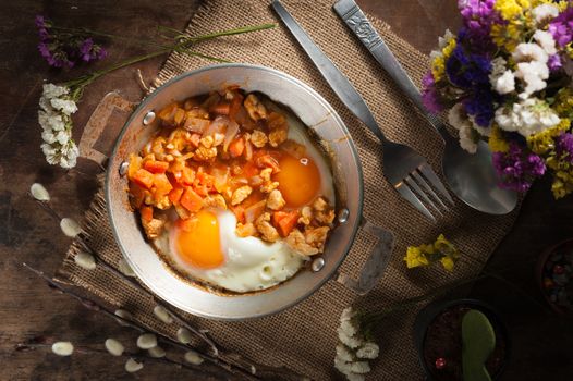 Vietnamese style fried egg in metal pan with white pork and onion on wood table in vintage style with low key scene