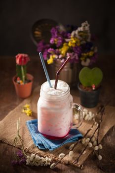 Fresh milk with red syrup on wood table in cafe with low key scene