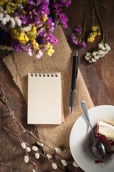 Small notepad with pen and pencil on rustic wood background with low key scene.