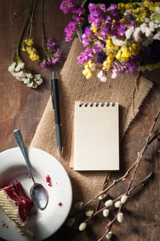 Small notepad with pen and pencil on rustic wood background with low key scene.