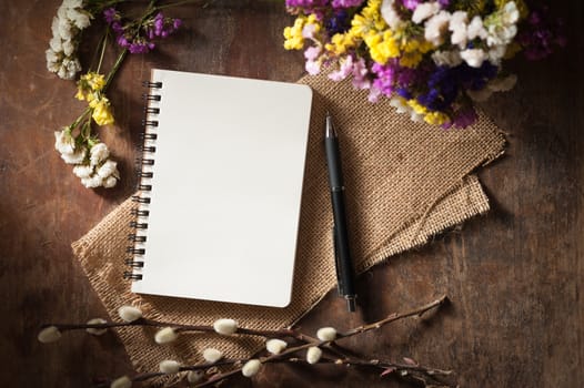 Small notepad with pen and pencil on rustic wood background with low key scene.
