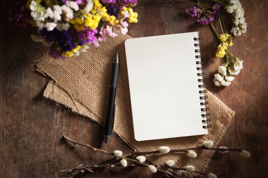 Small notepad with pen and pencil on rustic wood background with film filter effect