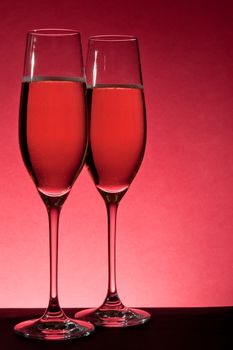 two full glasses of champagne over red background