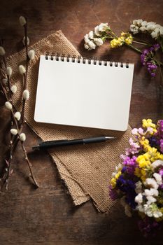 Small notepad with pen and pencil on rustic wood background with film filter effect