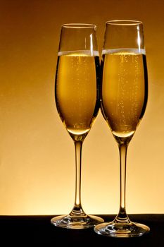 two elegant champagne glasses on golden background