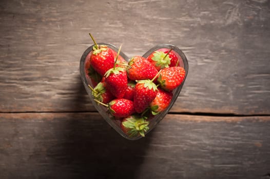 Strawberries on wood background in vintage style with low key scene.