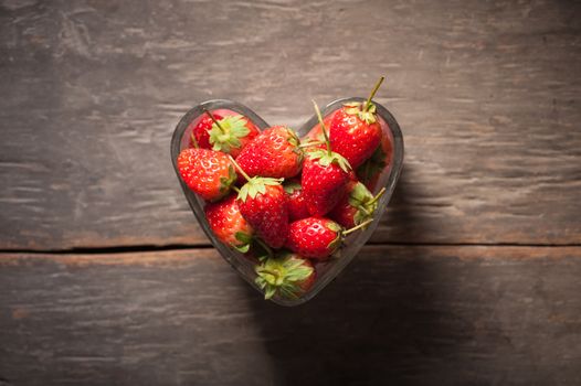 Strawberries on wood background in vintage style with low key scene.