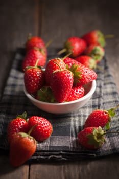Strawberries on wood background in vintage style with low key scene.