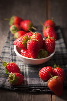 Strawberries on wood background in vintage style with low key scene.