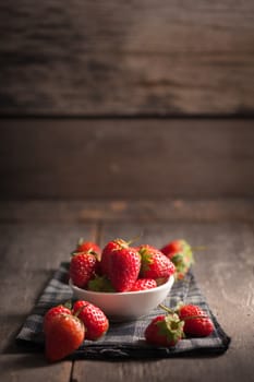 Strawberries on wood background in vintage style with low key scene.