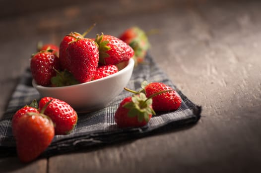 Strawberries on wood background in vintage style with low key scene.