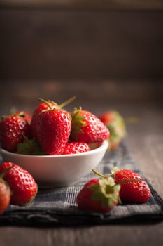 Strawberries on wood background in vintage style with low key scene.