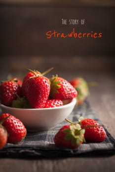 Strawberries on wood background with written words in vintage style with low key scene.