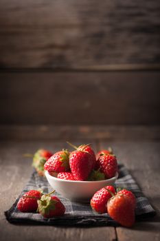 Strawberries on wood background in vintage style with low key scene.