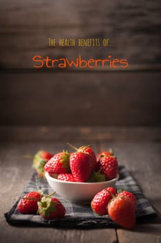 Strawberries on wood background with written words in vintage style with low key scene.
