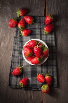 Strawberries on wood background in vintage style with low key scene.